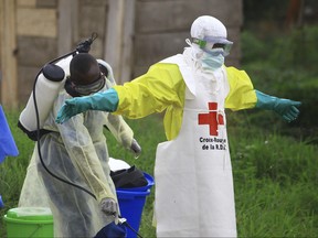 In this Sunday, Sept 9, 2018 file photo, a health worker sprays disinfectant on his colleague after working at an Ebola treatment center in Beni, eastern Congo. (AP Photo/Al-hadji Kudra Maliro, File)