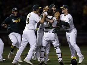 Oakland Athletics' Mike Fiers, centre, celebrates with Matt Olson (28) Chad Pinder (18) and Matt Chapman (26) after pitching a no hitter against the Cincinnati Reds at the end of a baseball game Tuesday, May 7, 2019, in Oakland, Calif.
