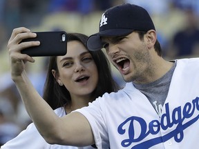 In this Oct. 19, 2016, file photo, Ashton Kutcher and wife Mila Kunis take a selfie before Game 4 of the National League Championship Series in Los Angeles. (AP Photo/David J. Phillip, File)