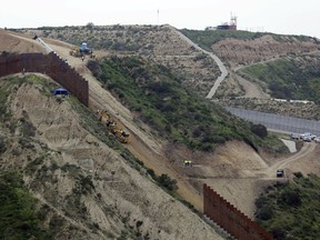 In this March 11, 2019, file photo, construction crews replace a section of the primary wall separating San Diego, above right, and Tijuana, Mexico, below left, seen from Tijuana, Mexico.