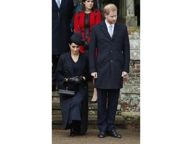 In this Tuesday, Dec. 25, 2018 file photo, Prince Harry, stands as Meghan, Duchess of Sussex curtsies to Queen Elizabeth II as she leaves in a car after attending the Christmas day service at St. Mary Magdalene Church in Sandringham in Norfolk, England.