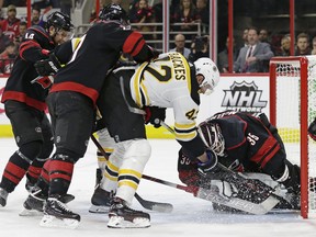 Boston Bruins' David Backes (42) tries to score against Carolina Hurricanes goalie Curtis McElhinney (35) while Hurricanes' Calvin de Haan (44) and Justin Faulk defend during the first period in Game 3 of the NHL hockey Stanley Cup Eastern Conference final series in Raleigh, N.C., Tuesday, May 14, 2019. (AP Photo/Gerry Broome)