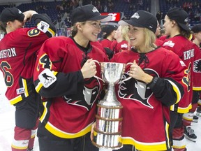 Calgary Inferno's Zoe Hickel (left) and Tori Hickel celebrate with the Clarkson Cup after beating Les Canadiennes de Montreal 5-2 in the CWHL final in Toronto, on March 24 , 2019.