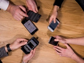 A file photo taken on Jan. 17, 2017, in Paris shows people holding their cell phones.