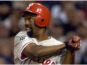 In this Aug. 4, 2004, file photo, Philadelphia Phillies' Doug Glanville follows through on an RBI triple hit off San Diego Padres pitcher Adam Eaton during the third inning in San Diego. The Chicago Cubs say they're investigating a fan using what appeared to be an offensive hand gesture associated with racism behind Glanville, now a television reporter, who was on the air for NBC Sports Chicago.