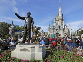In this Jan. 9, 2019 photo, guests watch a show near a statue of Walt Disney and Micky Mouse in front of the Cinderella Castle at the Magic Kingdom at Walt Disney World in Lake Buena Vista, part of the Orlando area in Fla. (AP Photo/John Raoux, File)