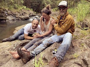 In this Friday, May 24, 2019, photo provided by Troy Jeffrey Helmer, shows Amanda Eller, second from left, after being found by searchers, Javier Cantellops, far left, and Chris Berquist, right, above the Kailua reservoir in East Maui, Hawaii, on Friday afternoon. (Troy Jeffrey Helmer/Find Amanda via AP)