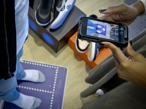 Nike officials demonstrate the company's foot-scanning tool on its app that will measure and remember the length, width and other dimensions of customers' feet after they point a smartphone camera to their toes, Wednesday April 24, 2019, in New York. (AP Photo/Bebeto Matthews)