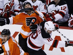 In this Jan. 8, 2011, file photo, Philadelphia Flyers' Daniel Carcillo, top, is hit in the face by a stick from New Jersey Devils' Rod Pelley during the third period of an NHL game in Philadelphia.