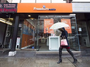 A women walks past the new rebranding sign of Freedom Mobile in Toronto on Thursday, November 24, 2016.