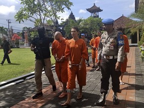 Police officers escort foreign nationals arrested for selling drugs prior to a press conference at the regional police headquarters in Denpasar, Bali, Indonesia, Friday, May 31, 2019.