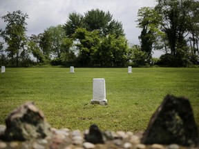 In this May 23, 2018 file photo, white markers, each indicating a mass grave of 150 people, are displayed on Hart Island in New York.
