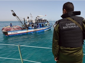 A member of the Tunisia's national guard stops a fishing boat in the sea bordering Tunisia and Libya as they check vessels for illegal migrants trying to reach Europe on May 5, 2015 off the coast of Tunisia's southeast port of Zarzis.