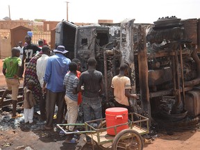 Residents look at a calcined tanker truck after an explosion which killed more than 55 people near the airport of Niamey on May 6, 2019.