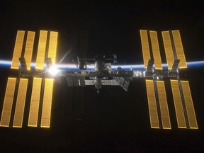 This March 25, 2009 photo provided by NASA shows the International Space Station seen from the Space Shuttle Discovery during separation. In the background is Earth's atmosphere seen as a blue arc. On Tuesday, April 30, 2019, NASA announced that a major power shortage at the station has delayed a SpaceX supply run later in the week. (NASA via AP)