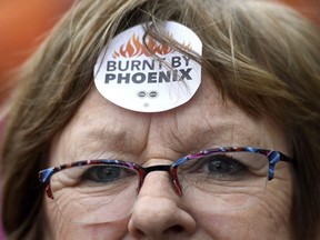 Shirley Taylor wears a "Burnt by Phoenix" sticker on her forehead during a rally against the Phoenix payroll system outside the offices of the Treasury Board of Canada in Ottawa on Februarty 28, 2018. Parliament's spending watchdog says the cost of building and putting in place a new pay system for federal civil servants should pale in comparison to stabilizing the failed Phoenix system.