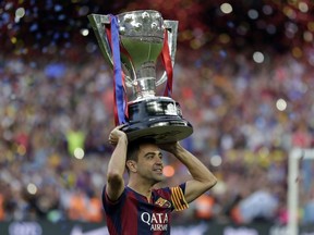 In this May 23, 2015 file photo, FC Barcelona's Xavi Hernandez holds up the trophy after winning the Spanish League title at the Camp Nou stadium in Barcelona, Spain. Midfielder Xavi Hernandez will retire from soccer this season at age 39, the former Spain and Barcelona great says. Xavi quit international football in 2014 and left Barcelona one year later after 17 seasons. He has since played for Al-Sadd in Qatar while preparing for a future as a manager.