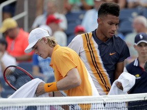 Denis Shapovalov, left, passes in front of Felix Auger-Aliassime, during their first-round match at the U.S. Open tennis tournament, Monday, Aug. 27, 2018, in New York. (AP Photo/Julio Cortez)