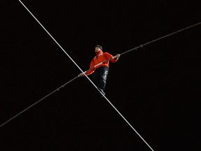 In this Nov. 2, 2014, file photo, Nik Wallenda walks on a tightrope uphill from the Marina City west tower across the Chicago River to the top of the Leo Burnett Building in Chicago.