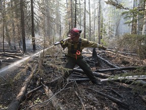 A firefighter extinguishes hotspots beside south of the town of High Level on May 25, 2019. Nearly 400 firefighters, 28 helicopters, and eight air tankers continue to battle northwest Alberta wildfires.