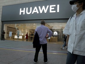 In this photo taken Monday, May 20, 2019, a man stands outside a Huawei store in Beijing. The Financial Times reported Friday, May 31, 2019 that tech giant Huawei has ordered its employees to cancel technical meetings with American contacts and has sent home numerous U.S. employees working at its Chinese headquarters.