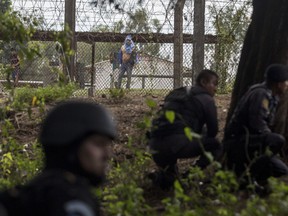Inmates inside the Pavon Rehabilitation Model Farm watch special task force police taking position on the perimeter after a shooting inside the jail in Fraijanes, Guatemala, Tuesday, May 7, 2019. Cecilio Chacaj of the municipal firefighters says that 10 prisoners were transported to medical facilities with bullet wounds.