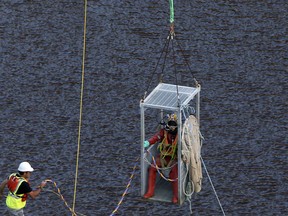A diver in a case dives with a lift in a man-made lake for search suitcases near the village of Mitsero outside of the capital Nicosia, Cyprus, Thursday, May 2, 2019.