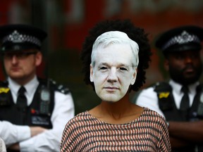 A demonstrator wearing a mask depicting Julian Assange protests as police officers stand guard outside of Westminster Magistrates Court, where a case hearing for U.S. extradition of Wikileaks founder Julian Assange is held, in London, June 14, 2019. REUTERS/Hannah Mckay