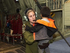 A member of the Canadian Armed Forces helps evacuate a child of the Pikangikum First Nation in Northern Ontario, as part of operation LENTUS on Thursday, May 30, 2019. Ontario's Ministry of Natural Resources says a wildfire threatening a remote Indigenous community in the province's northwest has grown several times larger.