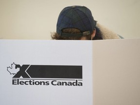 A woman marks her ballot behind a privacy barrier in the riding of Vaudreuil-Soulanges, west of Montreal, on election day on October 19, 2015.
