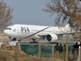 Pakistan policemen stand guard as a Pakistan International Airline (PIA) plane taxis on the runway on the way to Saudi Arabia during the PIA employees strike in Islamabad on February 8, 2016.