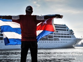 A man waves a Cuban flag at the Malecon waterfront as the first US-to-Cuba cruise ship to arrive in the island nation in decades glides into the port of Havana, on May 2, 2016. (ADALBERTO ROQUE/AFP/Getty Images)