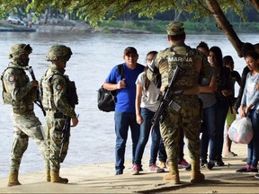 Members of Mexico's naval police talk to people that crossed the Suchiate River on a raft from Tecun Uman in Guatemala to Ciudad Hidalgo, Mexico on Sunday, June 16, 2019.