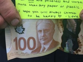 A person holds a $100 dollar bill and a note in this undated handout photo. A Nova Scotia community has been warmed by an anonymous gesture from a stranger who placed $100 bill and a message of positivity in a town park. The treasure was found by New Glasgow town employee Doug Miller while setting up for a funding announcement over the weekend.