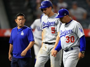 Manager Dave Roberts and the team trainer walk Corey Seager of the Los Angeles Dodgers off the field after he was injured at Angel Stadium of Anaheim on June 11, 2019 in Anaheim. (Sean M. Haffey/Getty Images)