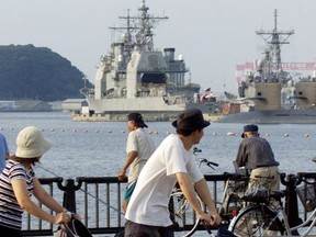 A family takes a stroll past the U.S. guided missile cruiser  Chancellorsville anchored at its home port of Yokosuka Naval Base, in  Yokosuka, south of Tokyo September 16, 2001.   REUTERS/Kimimasa Mayama/File Photo ORG XMIT: FW1