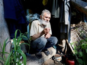 Former bargeman Viktor, 62, smokes near his wooden hut located in the Siberian Taiga area on a bank of the Yenisei River, outside Krasnoyarsk, Russia, on June 18, 2019.