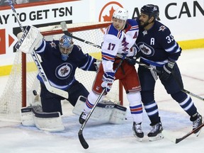 Winnipeg Jets goaltender Connor Hellebuyck makes a blocker save as defenceman Dustin Byfuglien (right) checks New York Rangers Jesper Fast in Winnipeg on Tues., Feb. 12, 2019. The Jets open their 2019-20 campaign with a four-game eastern road trip which starts against the Rangers. Kevin King/Winnipeg Sun/Postmedia Network