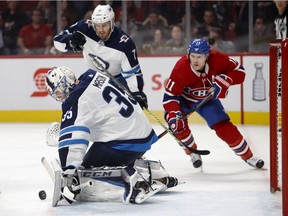 Winnipeg Jets goaltender Steve Mason gets his blocker on the puck as defenceman Ben Chiarot and Canadiens' Brendan Gallagher look for a rebound in Montreal on April 3, 2018.