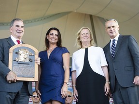 A member of the hall of fame committee holds the Hall of Fame plaque for 2019 inductee Roy Halladay, along with Brandy Halladay, widow of Roy, and baseball hall of fame chairman of the board Jane Forbes Clark and Baseball Commissioner Rob Manfred on Sunday.