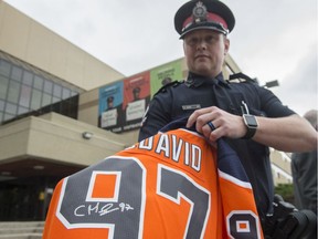 Const. Derek Burns with the Edmonton Police Service holds a Connor McDavid jersey with a fake signature on July 18, 2019.