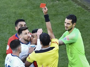 Paraguayan referee Mario Diaz de Vivar shows the red card to Argentina's Lionel Messi and Chile's Gary Medel as they have a physical encounter during the Copa America football tournament third-place match at the Corinthians Arena in Sao Paulo, Brazil, on July 6, 2019. (EVARISTO SA/AFP/Getty Images)