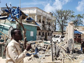 A man passes in front of the rubbles of the popular Medina hotel of Kismayo on July 13, 2019, a day after at least 26 people, including several foreigners, were killed and 56 injured in a suicide bomb and gun attack claimed by Al-Shabaab militants. - A suicide bomber rammed a vehicle loaded with explosives into the Medina hotel in the port town of Kismayo before several heavily armed gunmen forced their way inside, shooting as they went, authorities said.