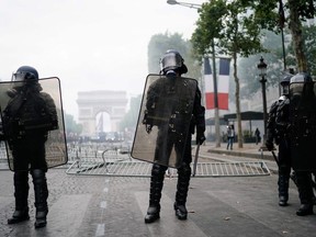 Members of the Gendarmerie stand in front of the Arc de Triomphe as protestors linked to the Yellow Vests (Gilets Jaunes) movement (unseen) take part in a demonstration on the side of the annual Bastille Day ceremony, on July 14, 2019, on the Champs-Elysees in Paris.