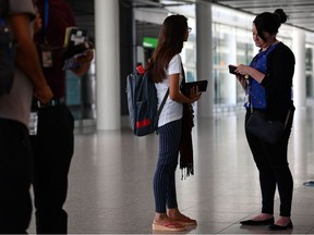 A official checks the passport of a passenger recently arrived from Mumbai in India in Terminal 2 at Heathrow Airport in London on July 16, 2019, part of Operation Limelight, a national multi-agency safeguarding operation at the UK border that focuses on harmful practices. - In collaboration with Border Force, specialist officers from the Met's Continuous Policing Improvement Command will be carrying out preventative and detection work in relation to inbound flights that have travelled from or via 'countries of prevalence' for forced marriage, female genital mutilation (FGM) and honour based abuse and breast ironing.