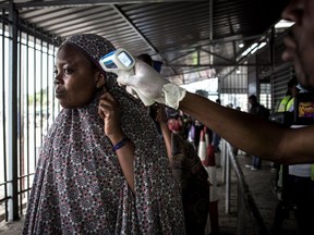 A woman gets her temperature measured at an Ebola screening station as she enters the Democratic Republic of the Congo from Rwanda on July 16, 2019 in Goma.