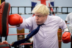 In this file photo taken on October 28, 2014 Mayor of London Boris Johnson boxes with a trainer during his visit to Fight for Peace Academy in North Woolwich, London. - Former London mayor Boris Johnson on July 23, 2019 won the race to become Britain's next prime minister, defeating Foreign Secretary Jeremy Hunt in the Conservative Party leadership contest. (LEON NEAL/Getty Images)