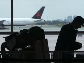 A passenger waits beside their luggage at the departure terminal at Toronto Pearson Airport, in Mississauga, Ont., Friday, May 24, 2019. Starting today, airline passengers can receive up to $2,400 if they'e bumped from a flight, part of a slew of air traveller protections beefing up compensation for travellers subjected to delayed flights and damaged luggage.