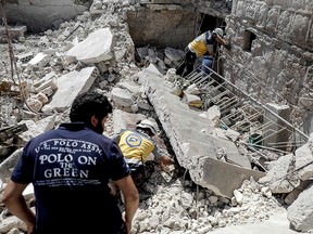 Members of the Syrian Civil Defence, also known as the "White Helmets," search for bodies or survivors in a collapsed building following a reported air strike by Syrian regime forces in Kafar Roma in the outskirts of Maaret al-Numan in the southern Idlib province on July 21, 2019.