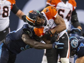 B.C. Lions running back John White IV (right) is tackled by the Toronto Argonauts during the first half last night at BMO Field. (Andrew Lahodynskyj/THE CANADIAN PRESS)